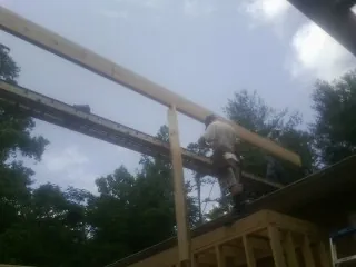 Carpenter setting a ridge beam over a new addition frame — Ice Dam Removal by Roofing Brothers in Camden Wyoming