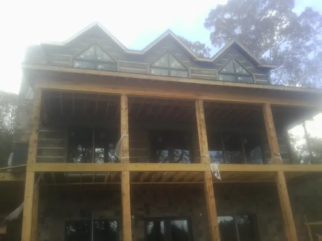 Dormers and porch framing on a large log home under construction — Roof Coating work by our crew in Camden Wyoming