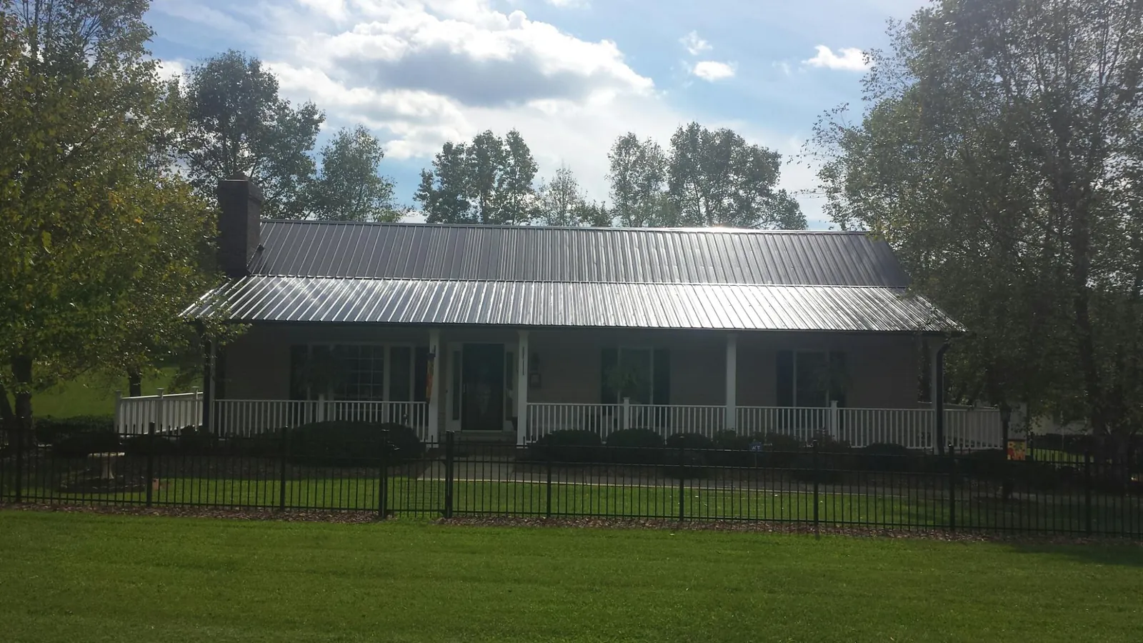 Gray metal roof on a brick ranch with a full width front porch — Gutter Guard Installation work by our crew in Camden Wyoming