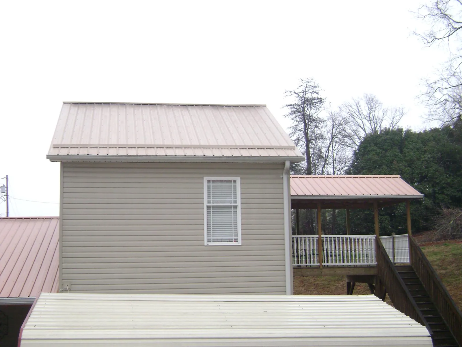 Tan metal roofs on a two story addition and attached porch, from a Roof Replacement job in Camden Wyoming